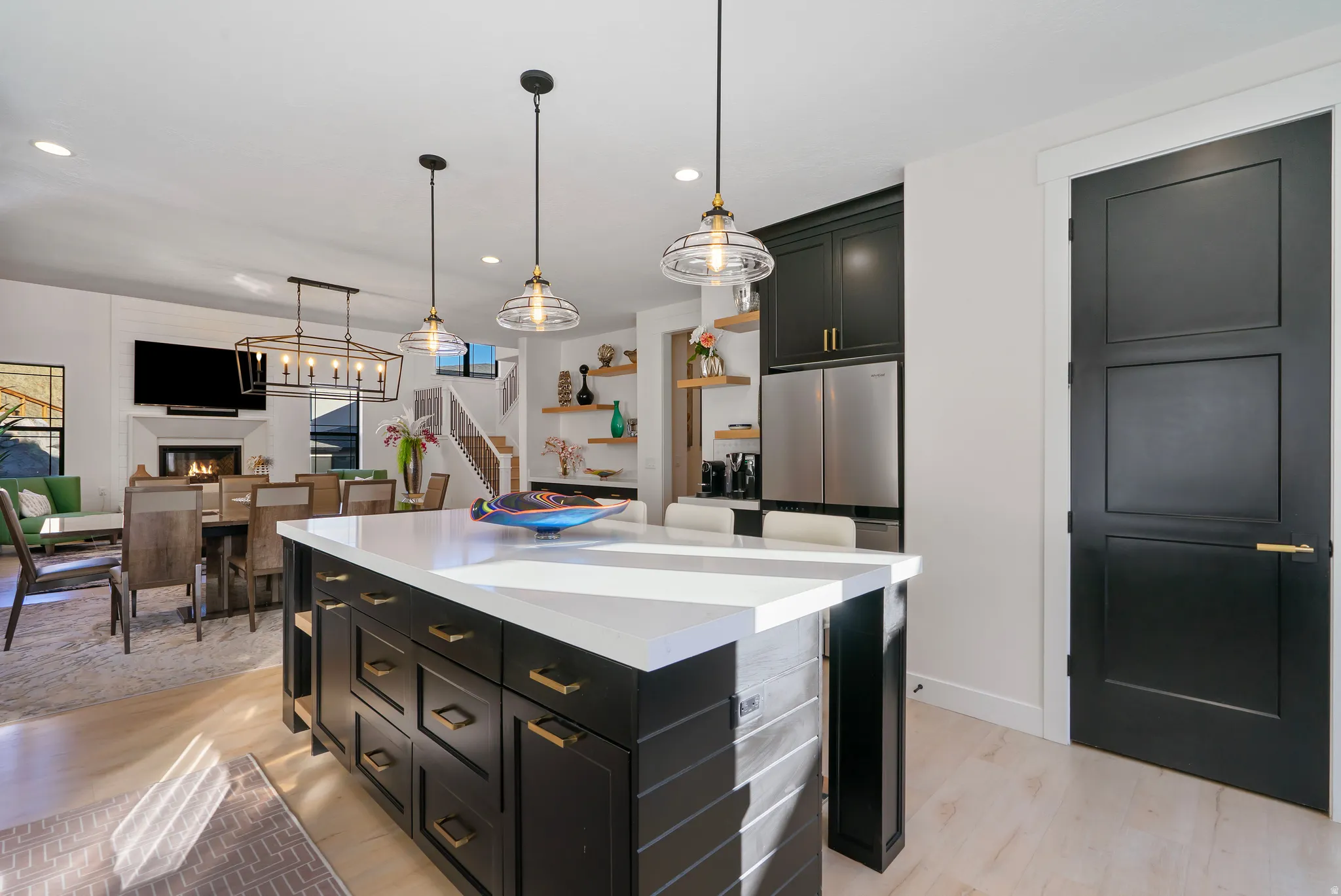 Kitchen island featuring a white countertop, dark cabinetry, and brass-finished hardware