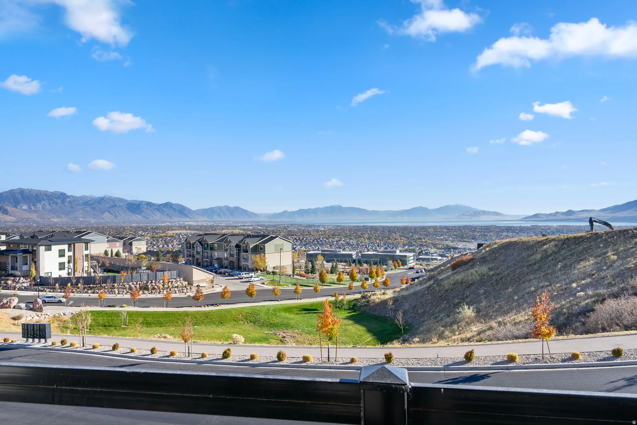 Expansive city and mountain scenery featuring distant water, residential structures, and paved roadways