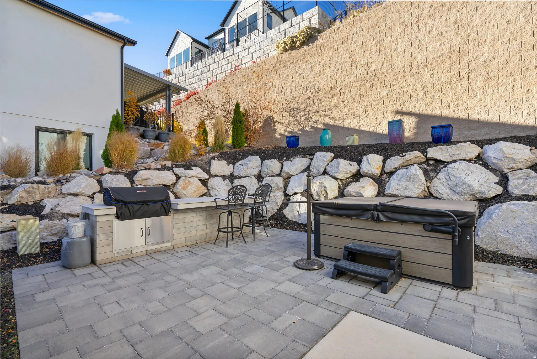Spacious paver patio featuring an outdoor kitchen with built-in grill and counter seating