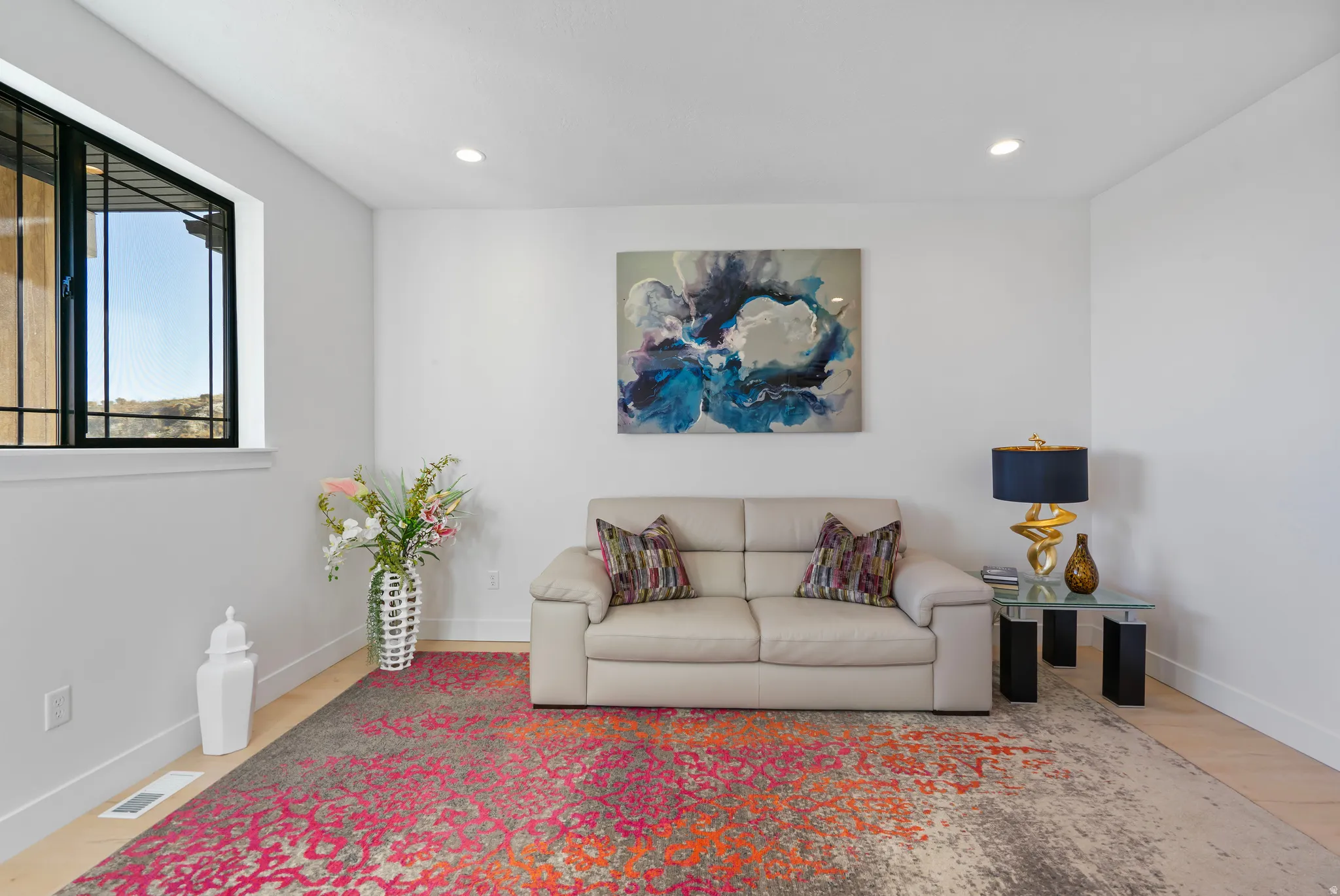 Spacious room with light wood-finish flooring, recessed lighting, and a large window with black grilles