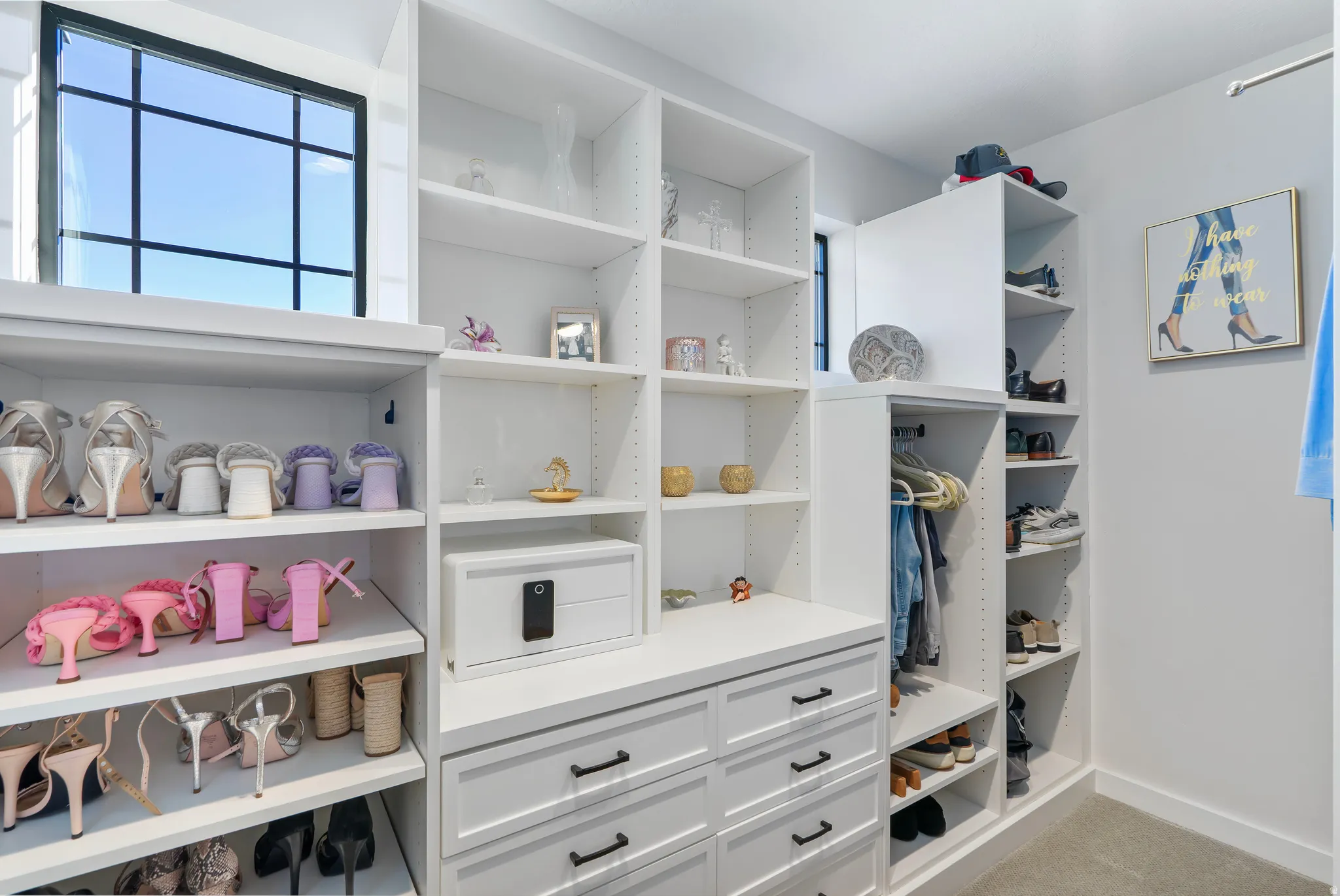 Custom closet system featuring extensive shelving, built-in drawers with dark hardware, dedicated shoe storage, and a large window with black grid panes