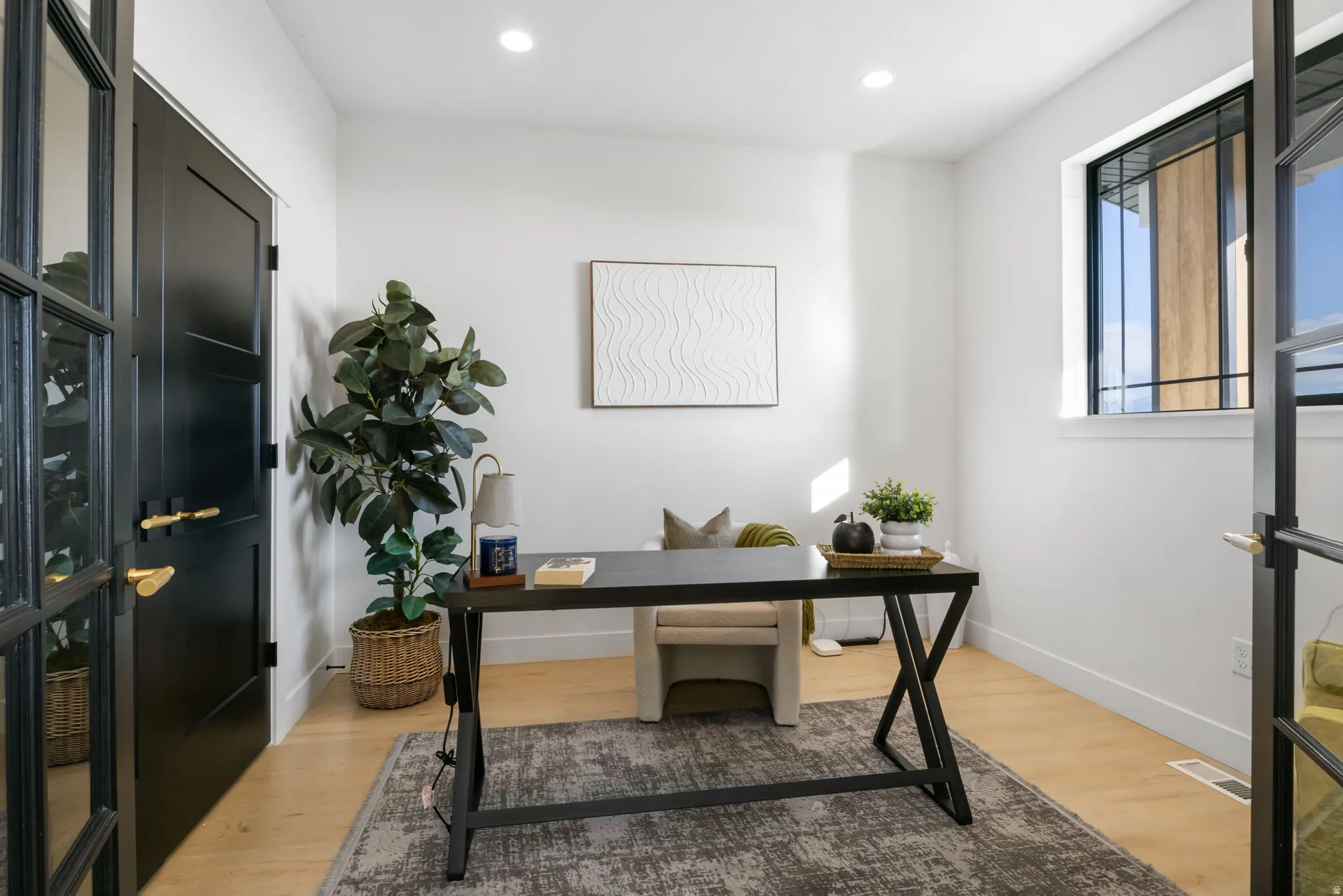Room featuring light wood-finish flooring, recessed lighting, and a window with dark trim