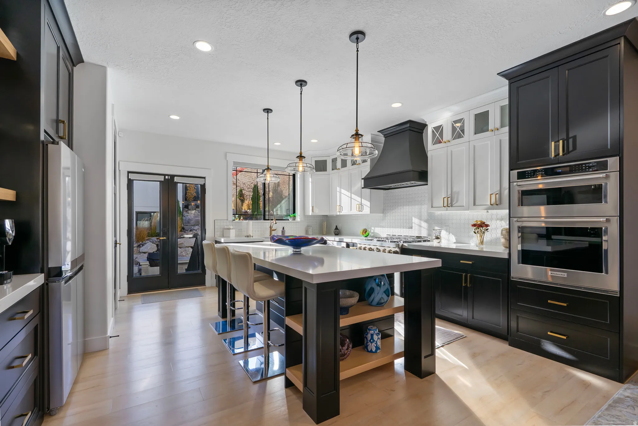 Contemporary kitchen featuring a large central island with seating, light wood-finish flooring, and recessed lighting