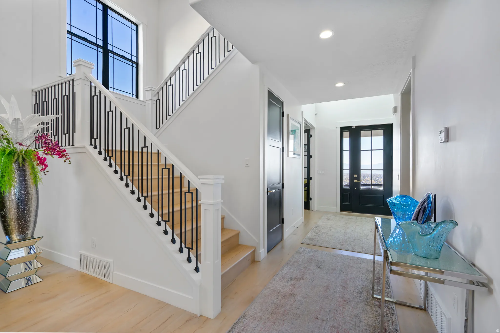 Entry foyer featuring a prominent staircase with black wrought iron balusters and light wood treads