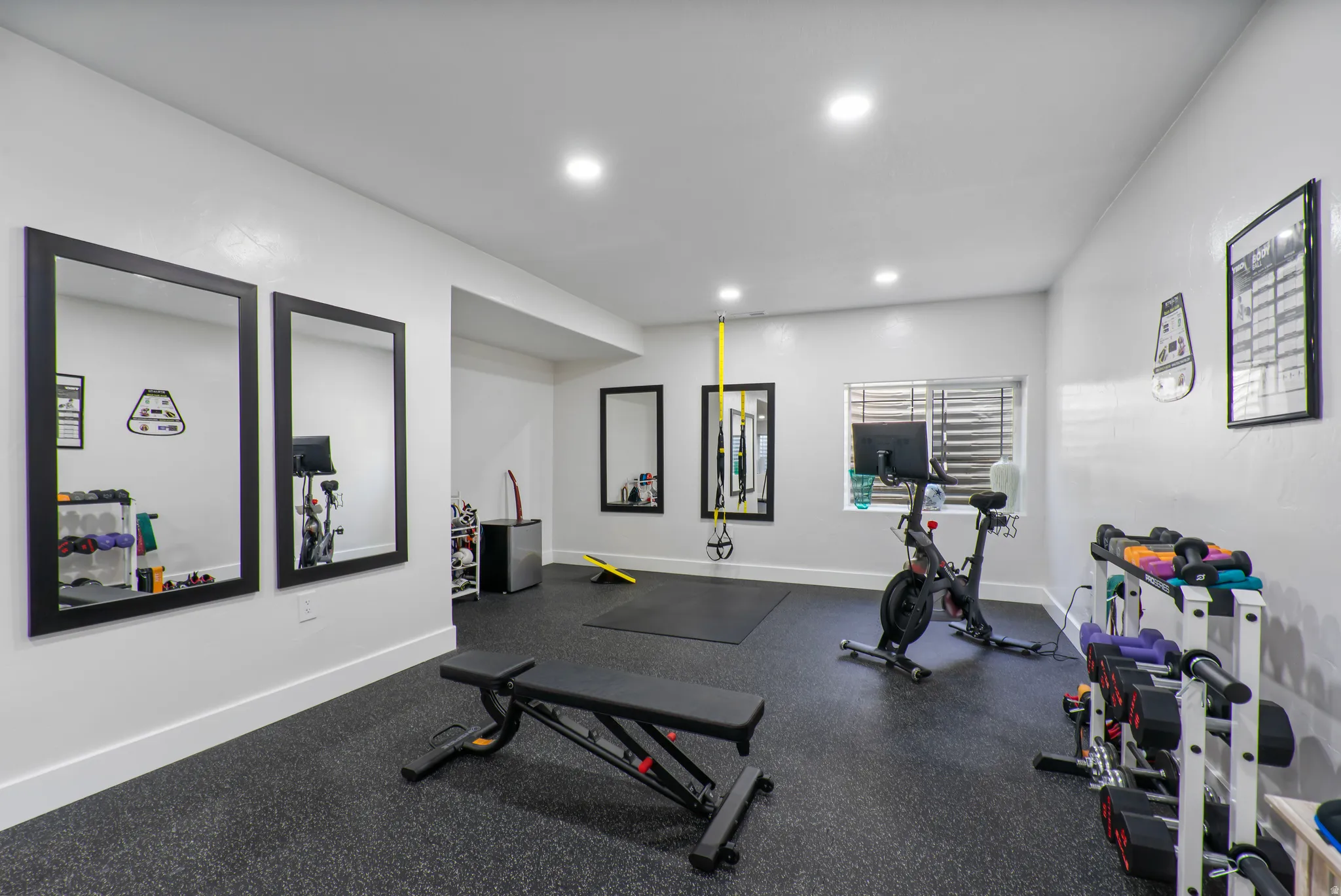 Dedicated fitness space featuring rubber flooring, recessed lighting, and multiple wall-mounted mirrors