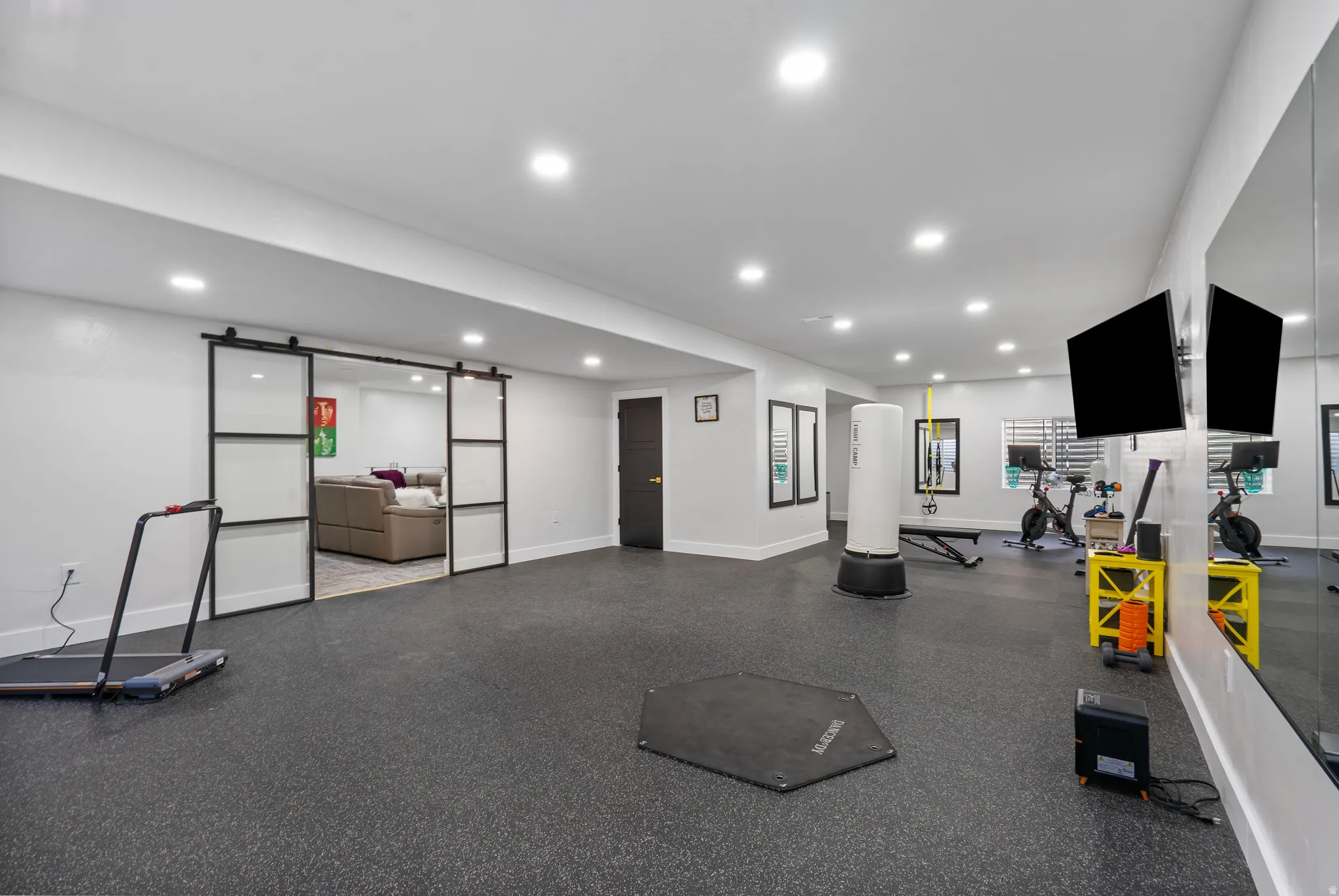 Spacious recreation room featuring dark rubberized flooring and recessed lighting