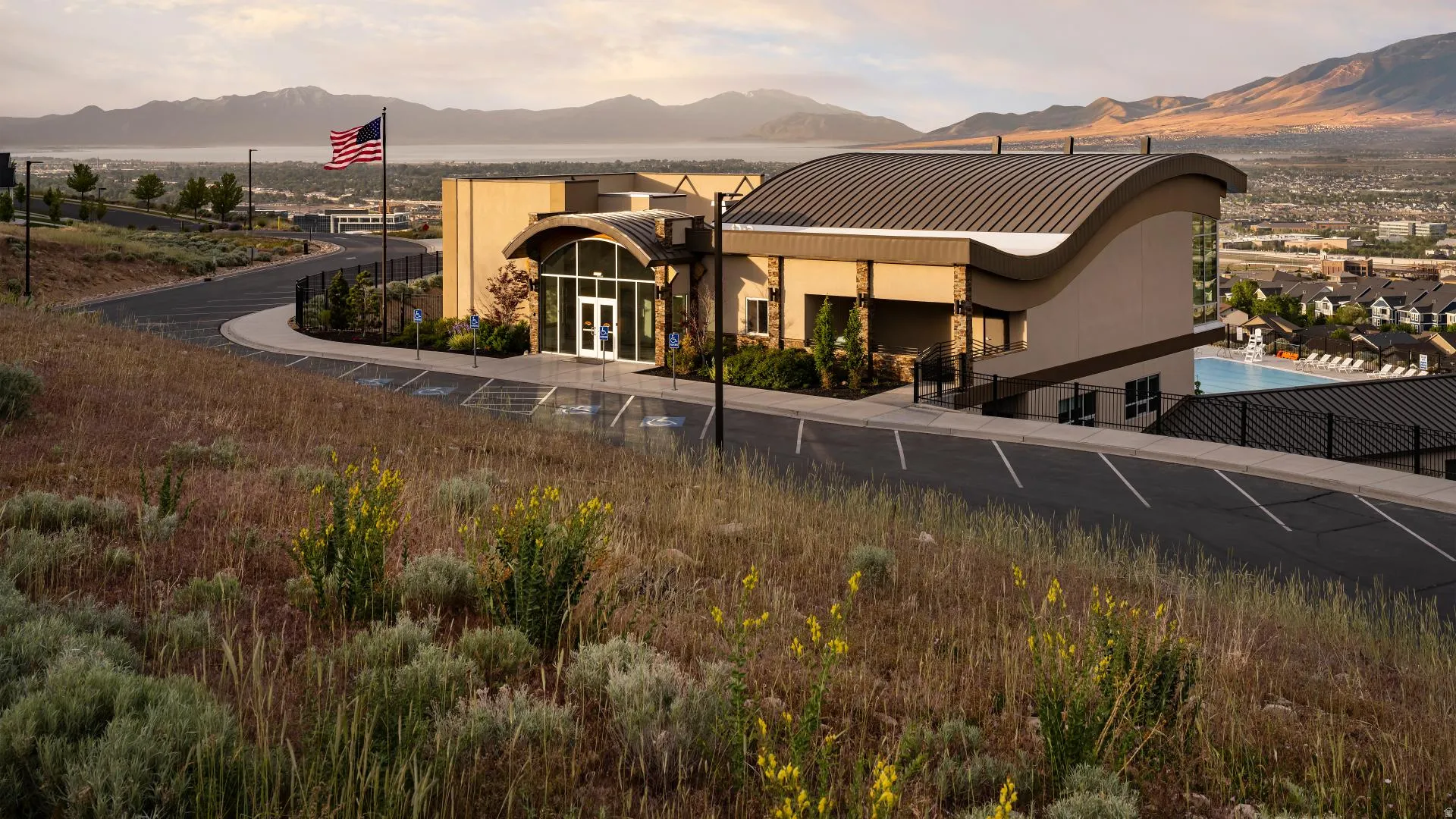 HOA Amenities Modern building featuring a distinctive curved roofline, expansive glass entry, and a multi-level design