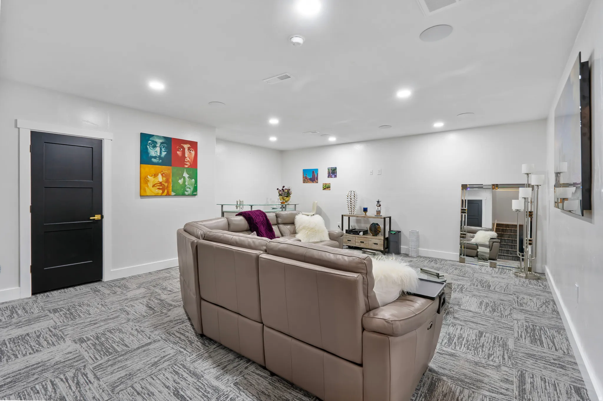 Spacious interior featuring recessed lighting, a modern black three-panel door with white trim, and patterned carpet flooring