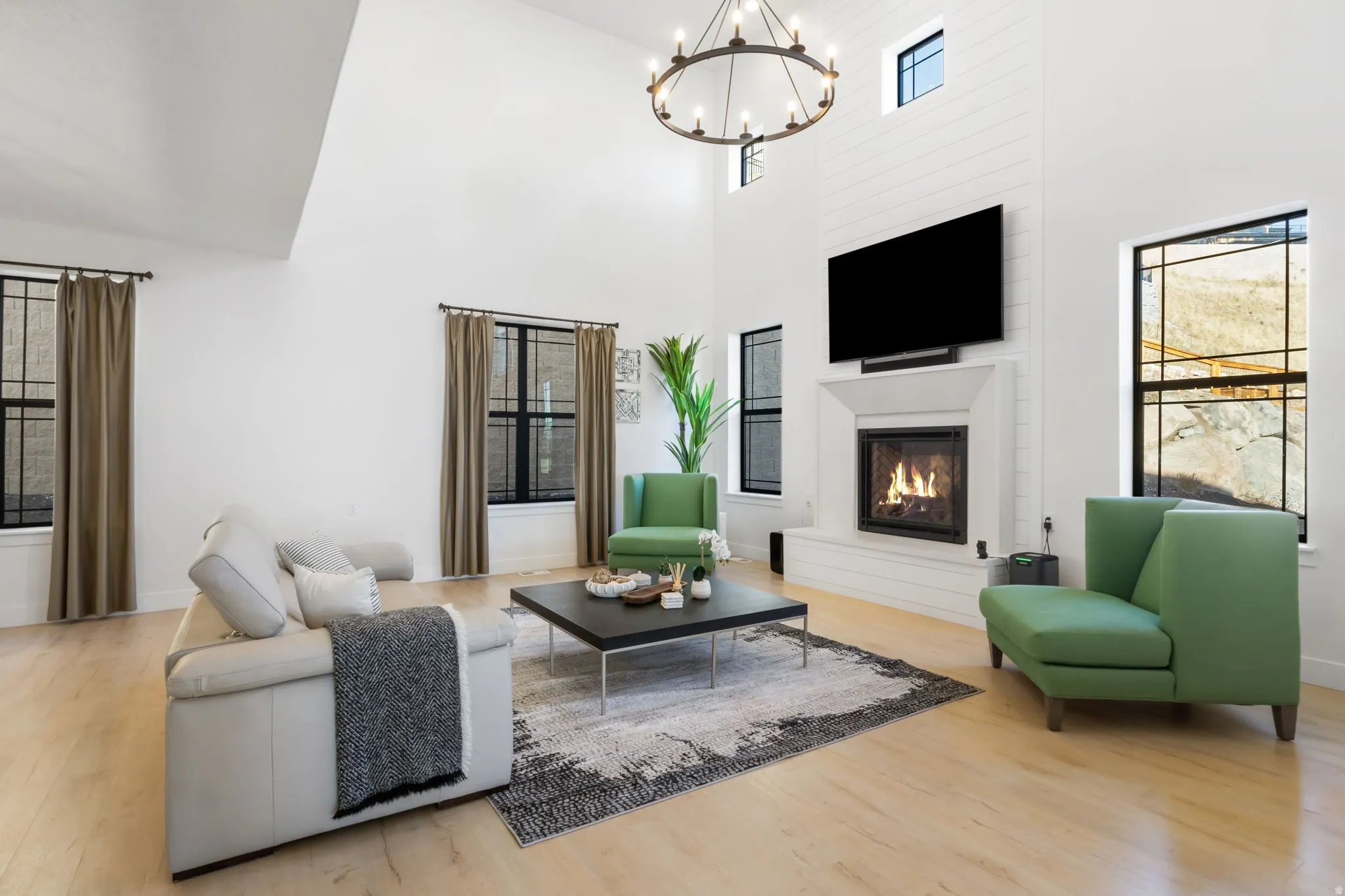 Bright, open living room showcasing soaring vaulted ceilings with skylights, hardwood flooring, and a gas fireplace with built-in surround