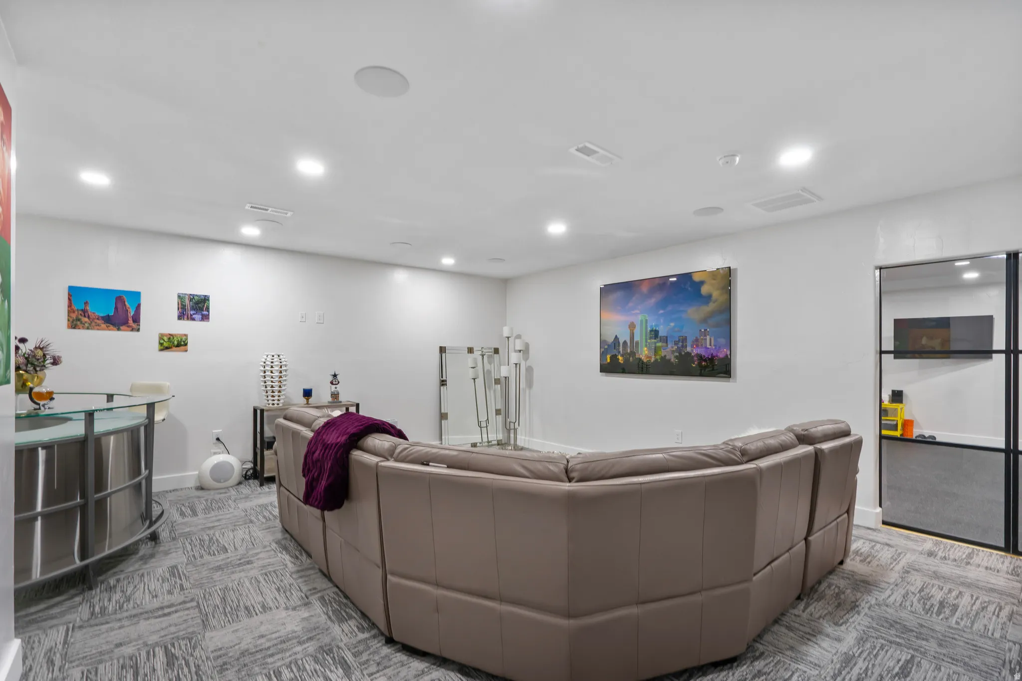 Spacious entertainment area featuring recessed lighting, a modern glass-top bar, and gray patterned flooring