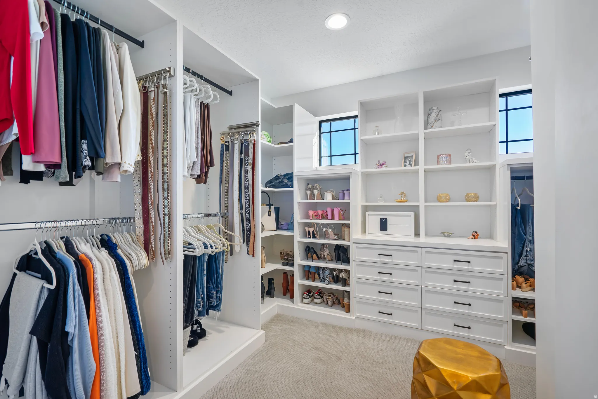 Custom closet system featuring extensive shelving, built-in drawers, multiple hanging rods, corner shelving, and upper windows for natural light