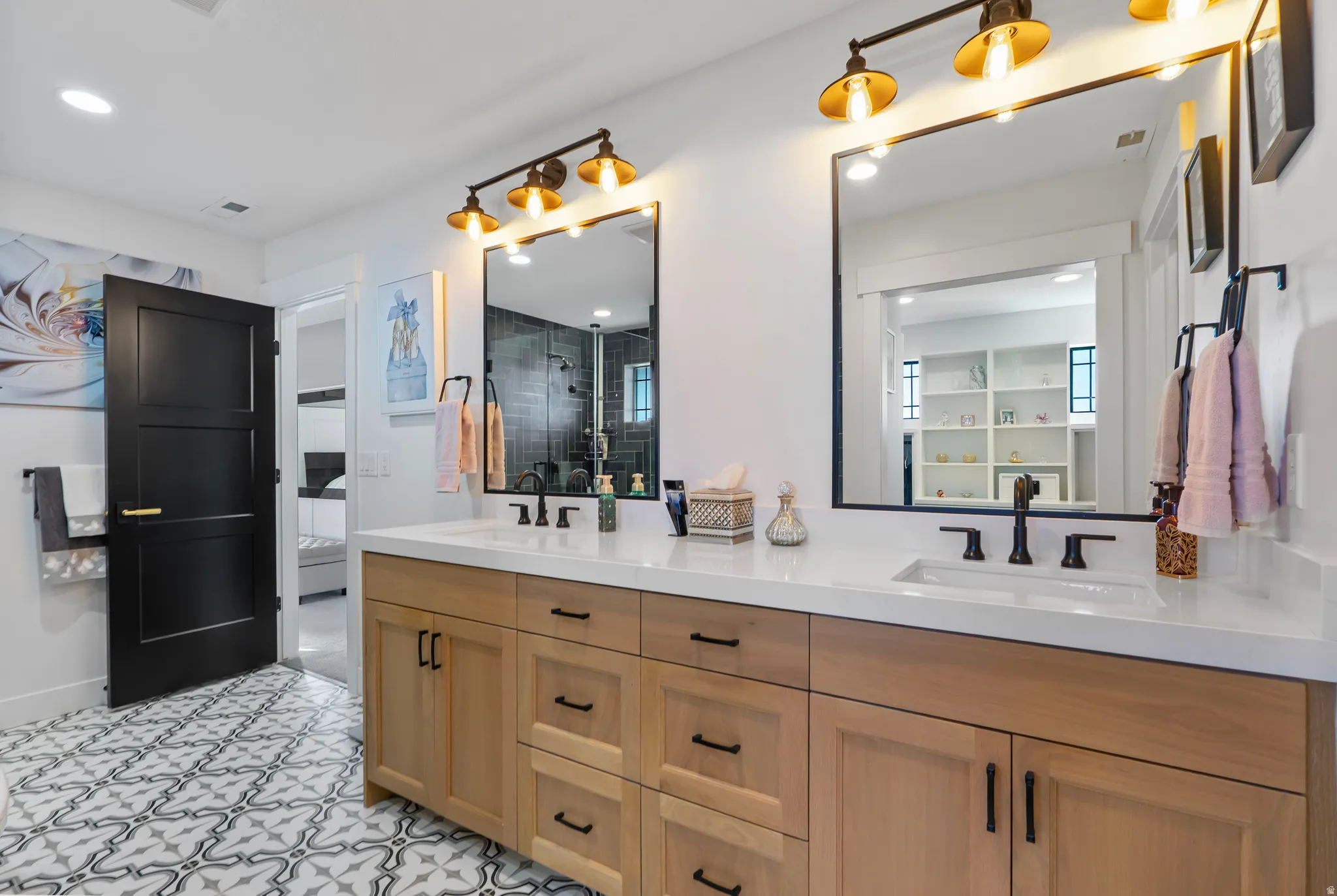Double vanity with light wood-finish cabinetry, white countertops, and dual undermount sinks