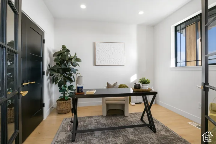 Room featuring light wood-finish flooring, recessed lighting, and a window with dark trim