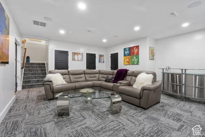 Spacious room featuring patterned carpet flooring, recessed lighting, and a built-in bar area with a glass countertop