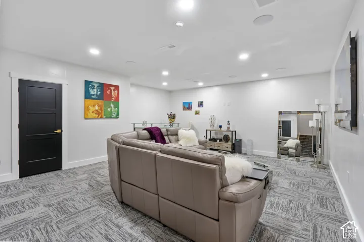 Spacious interior featuring recessed lighting, a modern black three-panel door with white trim, and patterned carpet flooring