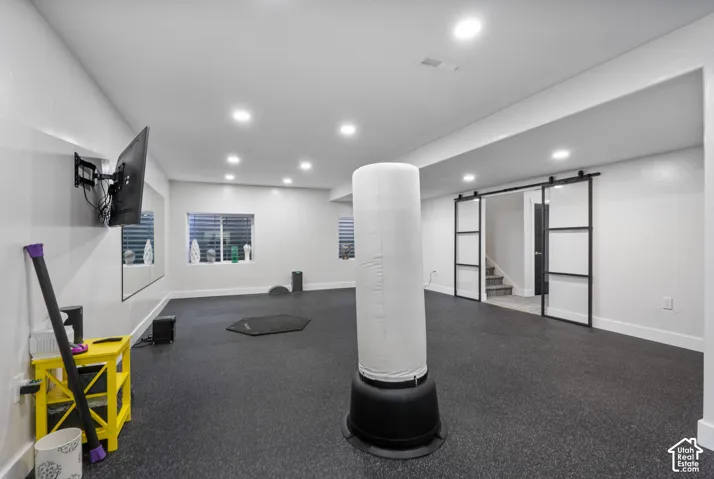 Expansive room featuring black rubber flooring, recessed lighting, and wall-mounted television