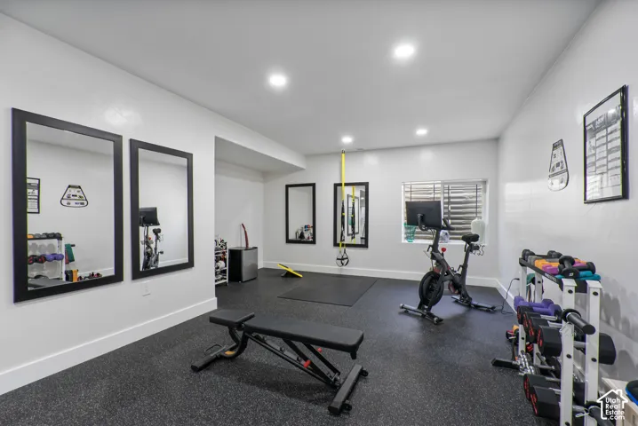 Dedicated fitness space featuring rubber flooring, recessed lighting, and multiple wall-mounted mirrors