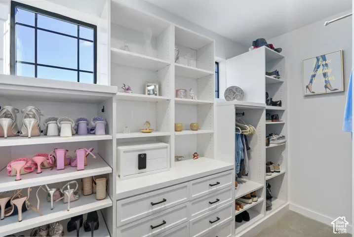 Custom closet system featuring extensive shelving, built-in drawers with dark hardware, dedicated shoe storage, and a large window with black grid panes