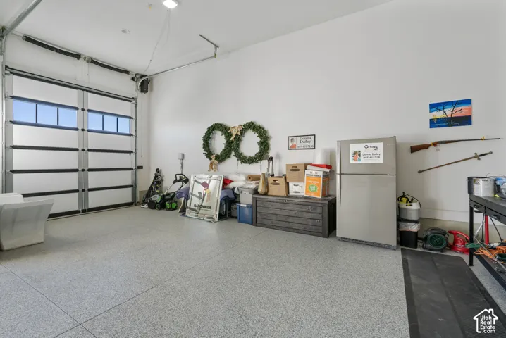Garage featuring a sectional overhead door with upper horizontal window panels and a light gray epoxy flooring