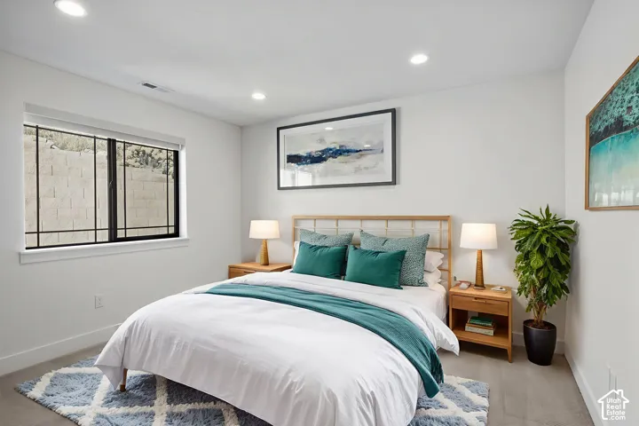 Recessed lighting illuminates this bright room featuring a window with security bars, light-toned flooring, and crisp white walls