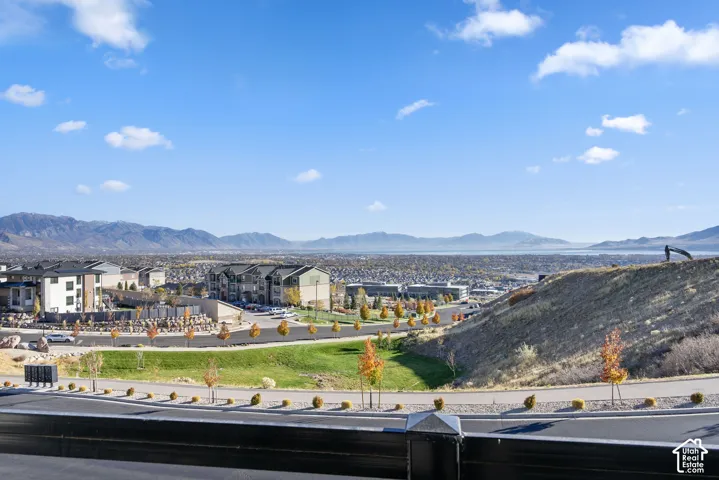 Expansive city and mountain scenery featuring distant water, residential structures, and paved roadways