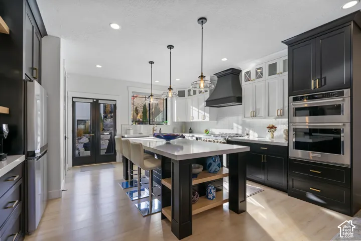 Contemporary kitchen featuring a large central island with seating, light wood-finish flooring, and recessed lighting