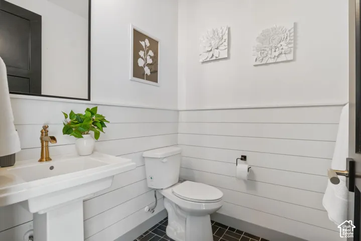 Bathroom with a pedestal sink, brass faucet, and black-framed mirror