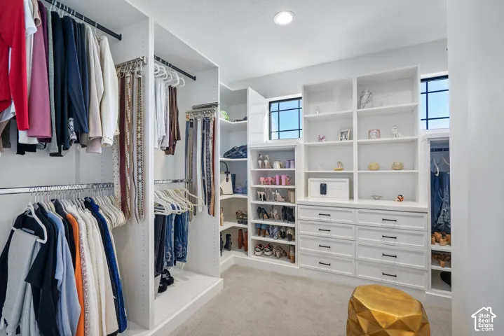 Custom closet system featuring extensive shelving, built-in drawers, multiple hanging rods, corner shelving, and upper windows for natural light