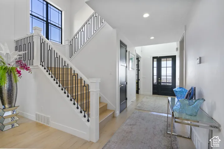 Entry foyer featuring a prominent staircase with black wrought iron balusters and light wood treads
