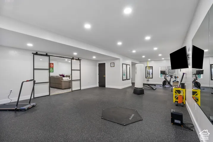 Spacious recreation room featuring dark rubberized flooring and recessed lighting