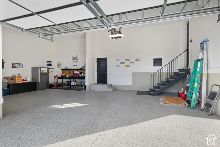 Spacious garage featuring a durable epoxy-coated floor, automatic overhead door, and direct access door