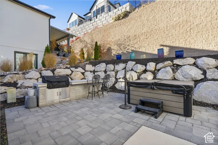 Spacious paver patio featuring an outdoor kitchen with built-in grill and counter seating