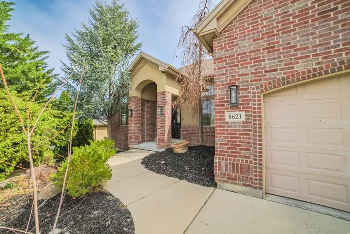 Brick exterior with a covered entry, stucco archway, and a paved walkway