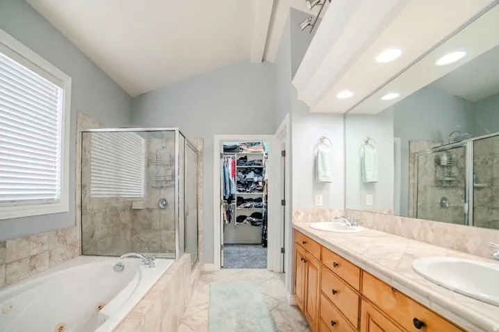 Bathroom featuring a dual vanity with light wood cabinetry, a large mirror, and recessed lighting