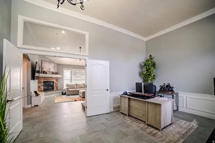 Spacious room featuring tile flooring, white wainscoting, and crown molding