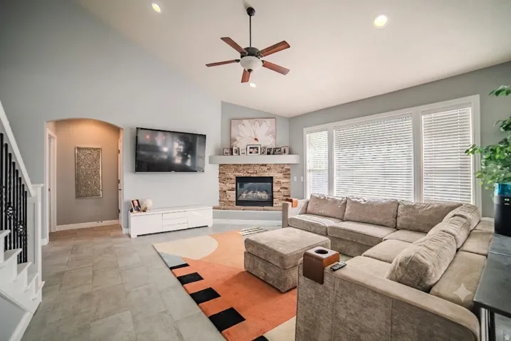 Living area featuring vaulted ceilings with recessed lighting, a ceiling fan, and large windows with horizontal blinds