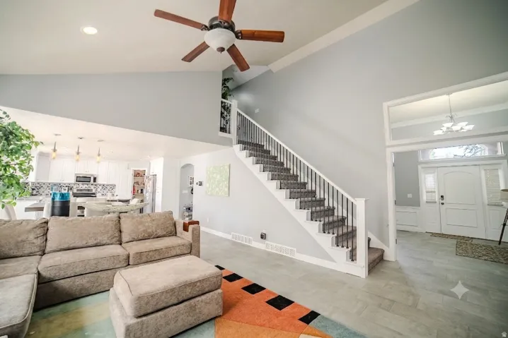 Vaulted great room featuring wood-finish ceiling fan and light tile flooring