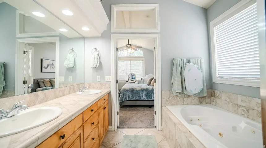 Dual vanity with undermount sinks and wood cabinetry, set against a stone-finish countertop and backsplash