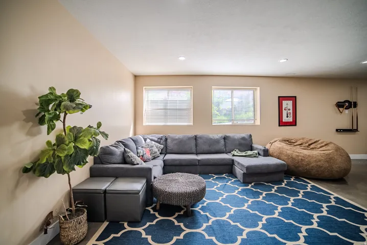 Recessed lighting illuminating a spacious room with light-toned walls and two windows fitted with horizontal blinds