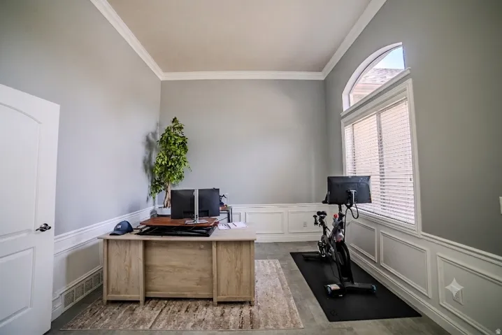 Room featuring crown molding, wainscoting, an arched transom window, and a paneled door