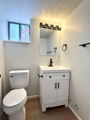 Bathroom featuring a white vanity with black hardware, a black faucet, and a black-framed mirror with multi-bulb lighting