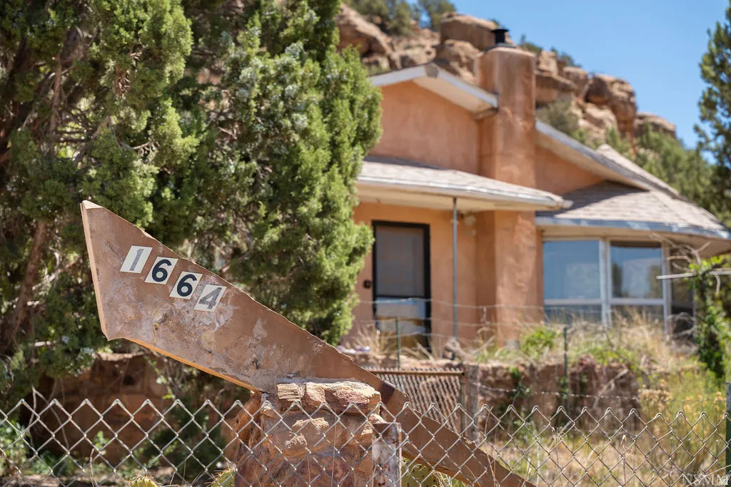 Stucco exterior residence with a partial chain-link fence and address marker
