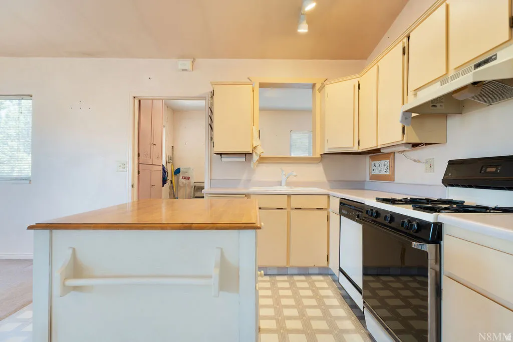Kitchen with a central island featuring a wood-finish countertop