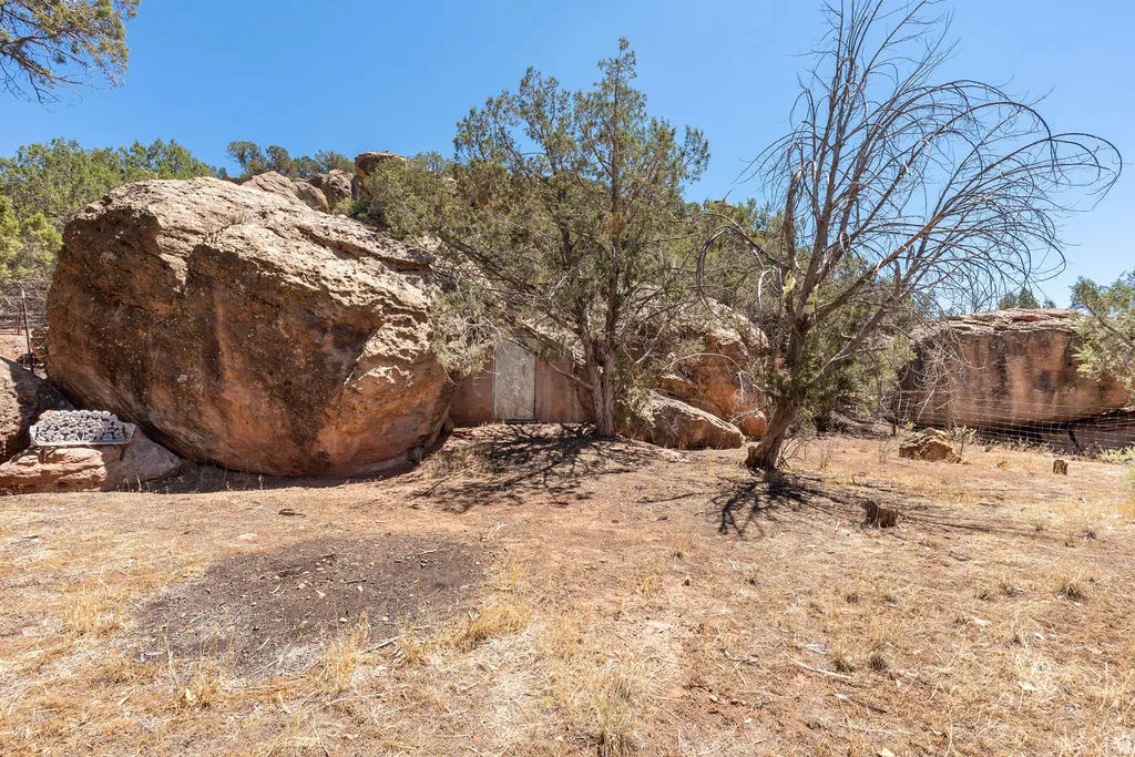 Natural rock formations and mature native trees define this arid landscape, featuring exposed earth and dry brush