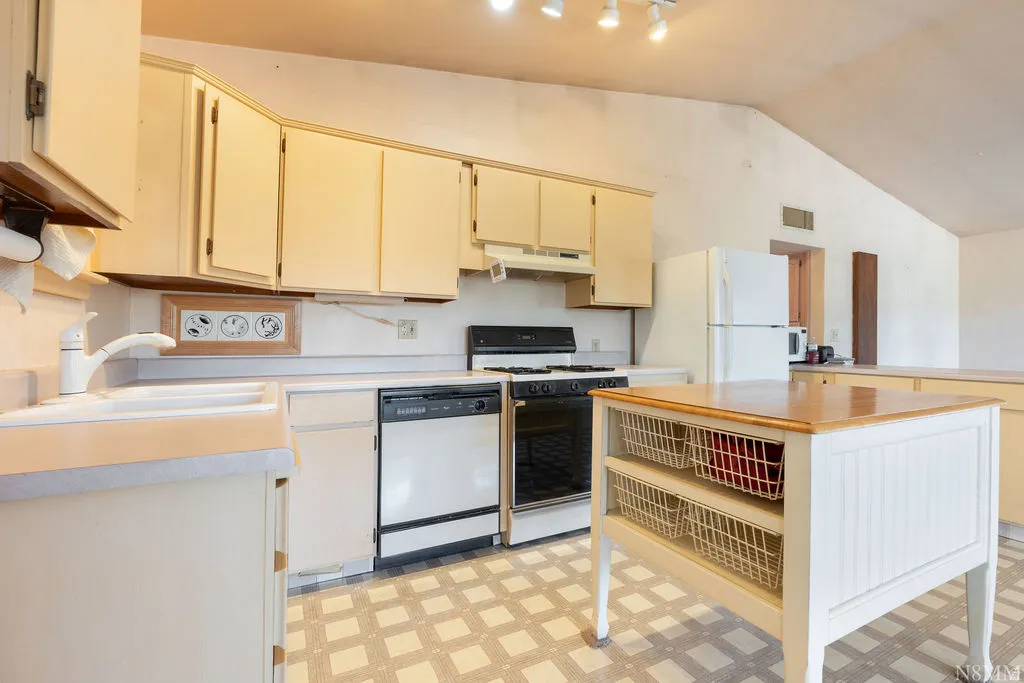 Kitchen featuring light-toned cabinetry, a built-in dishwasher, and a freestanding range