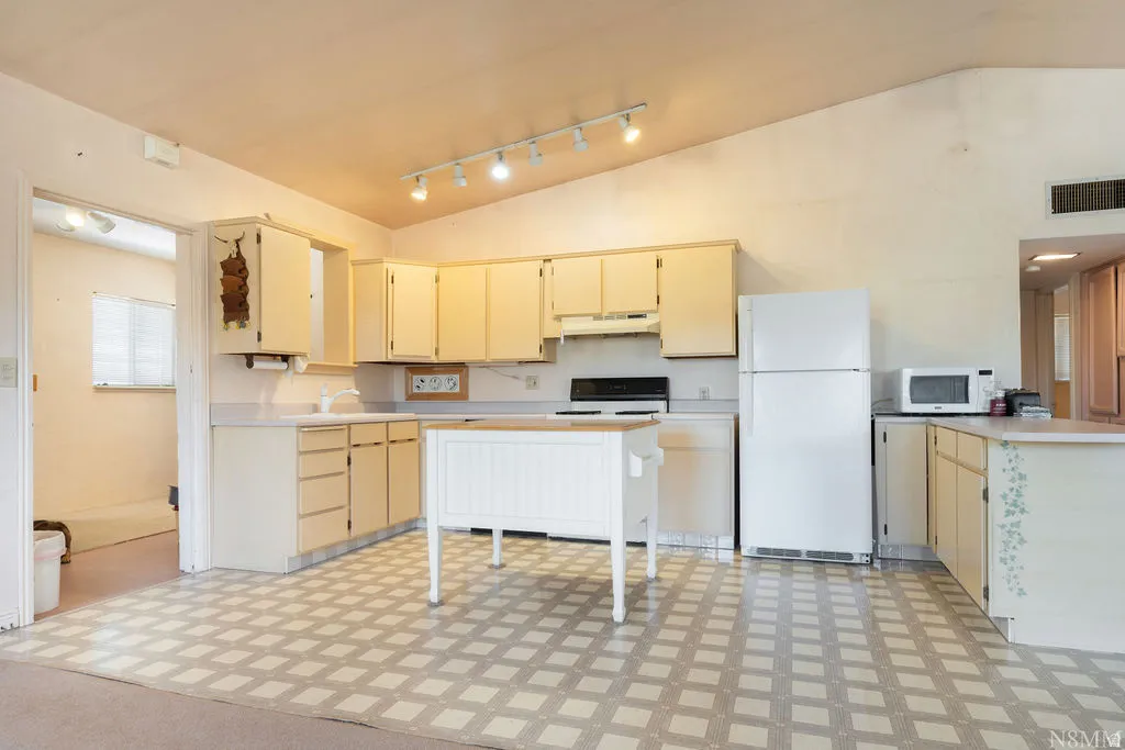 Kitchen featuring an angled ceiling, track lighting, and patterned tile flooring
