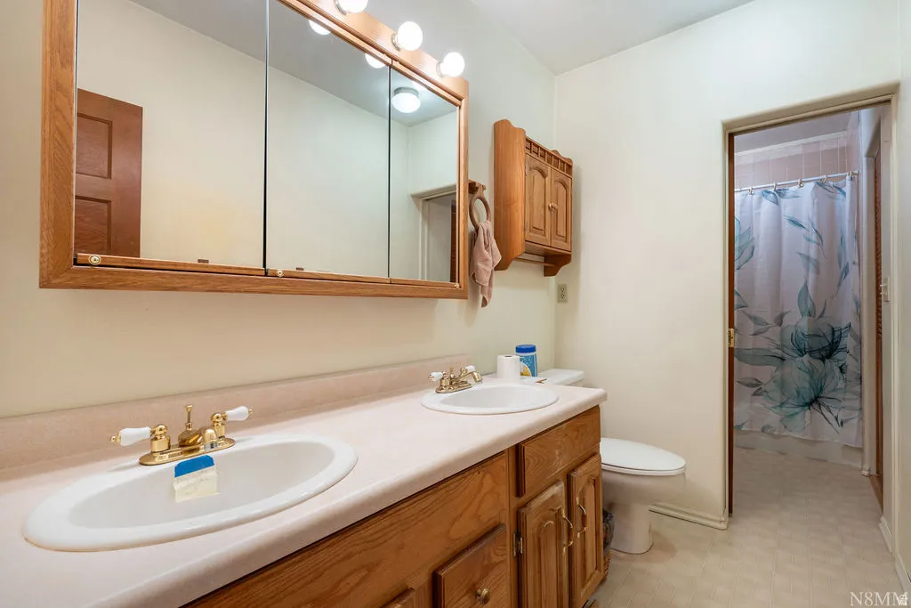 Dual-sink vanity with wood cabinetry, integrated undermount basins, and polished brass fixtures