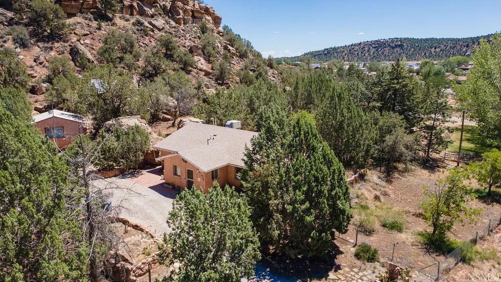 Southwestern-style residence featuring a light-colored roof and brick-look patio