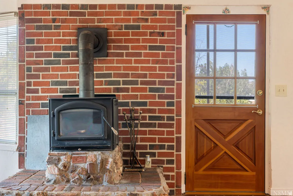Brick-clad wall featuring a black wood-burning stove with a stone and brick hearth