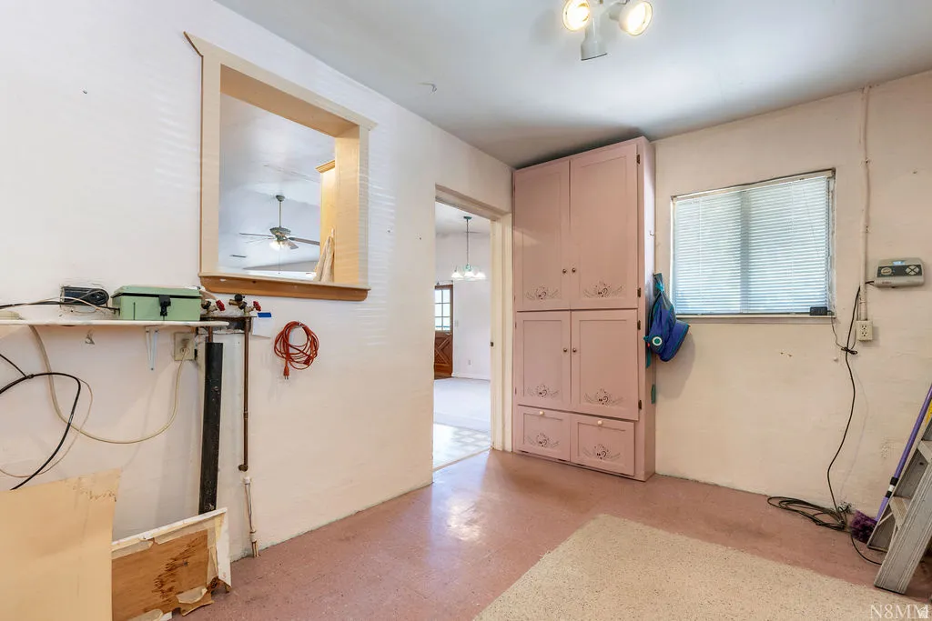 Room featuring built-in cabinetry, a window with blinds, and an interior pass-through window with wood trim